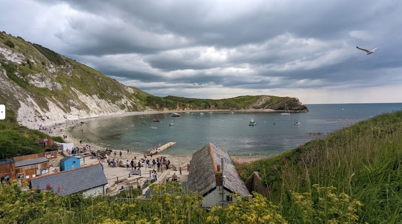 Lulworth Cove, with boats in the sheltered bay and white cliffs